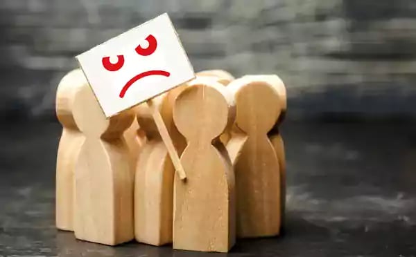 Wooden people figures with an unhappy face sign.