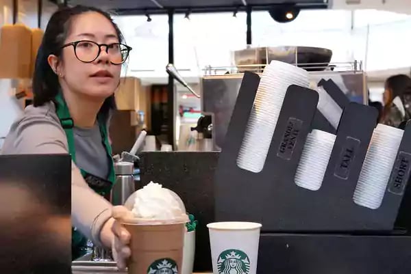 Barista handing a coffee drink to a customer.
