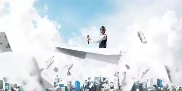 Person flying in the air on a paper airplane.