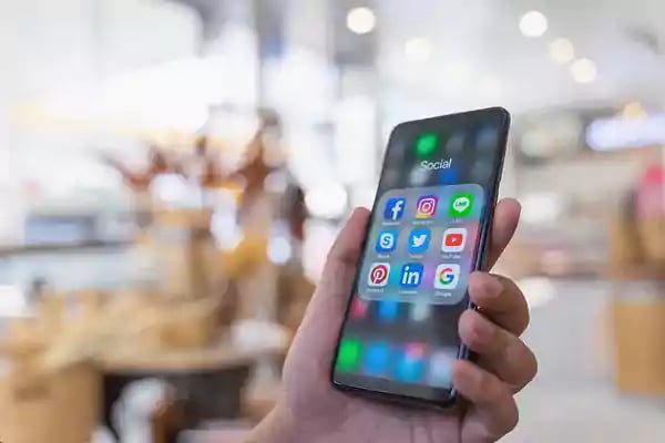 Person holding a phone with social icons on display.
