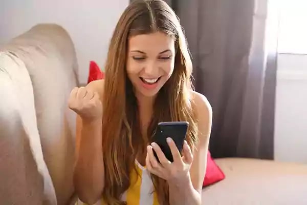 Woman cheering while looking at her phone.