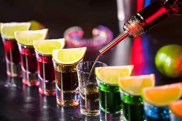 Line of shot glasses on a bar.