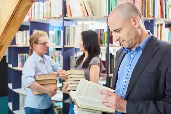Group of people in a library reading books.